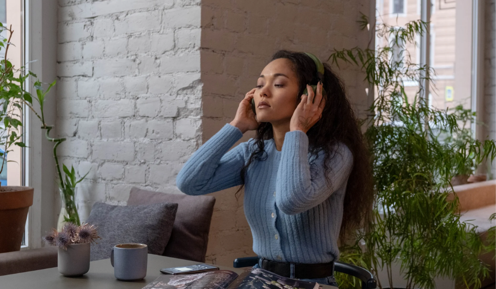 Woman listening to music with headphones by a window