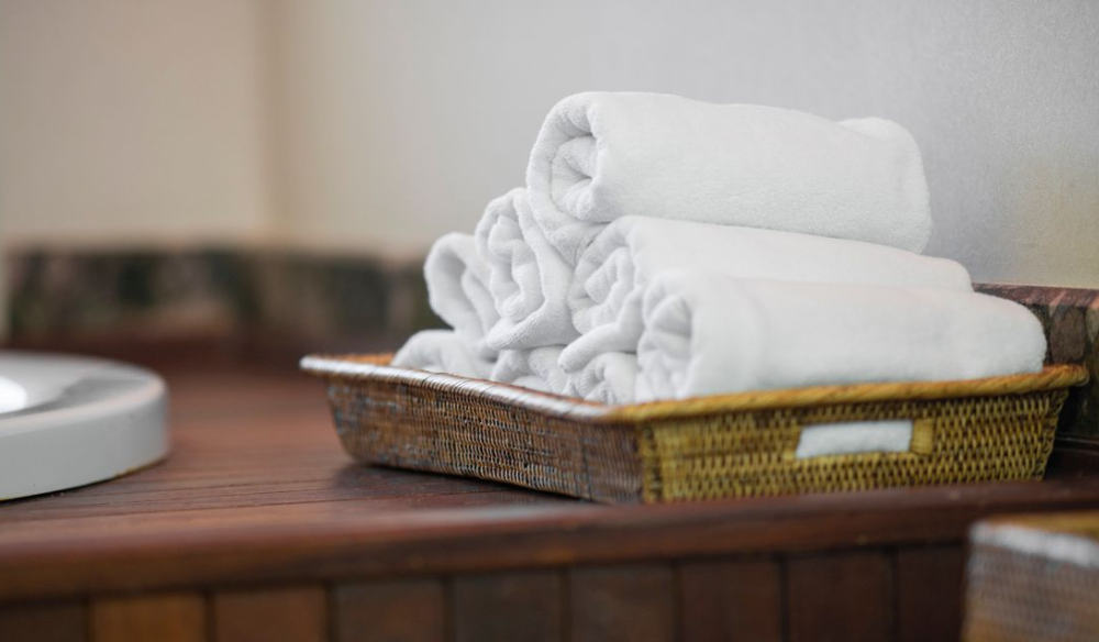Rolled white towels in a basket on a spa counter