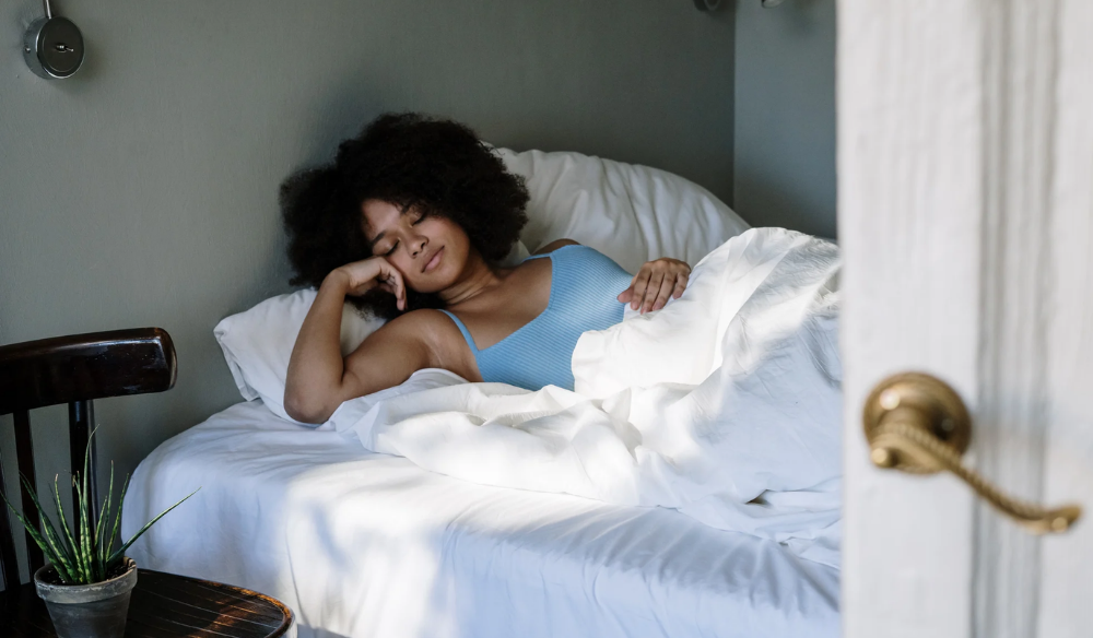 Woman resting in bed by a bright window