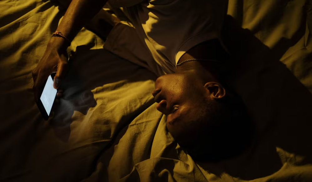 Person lying in bed at night using a tablet