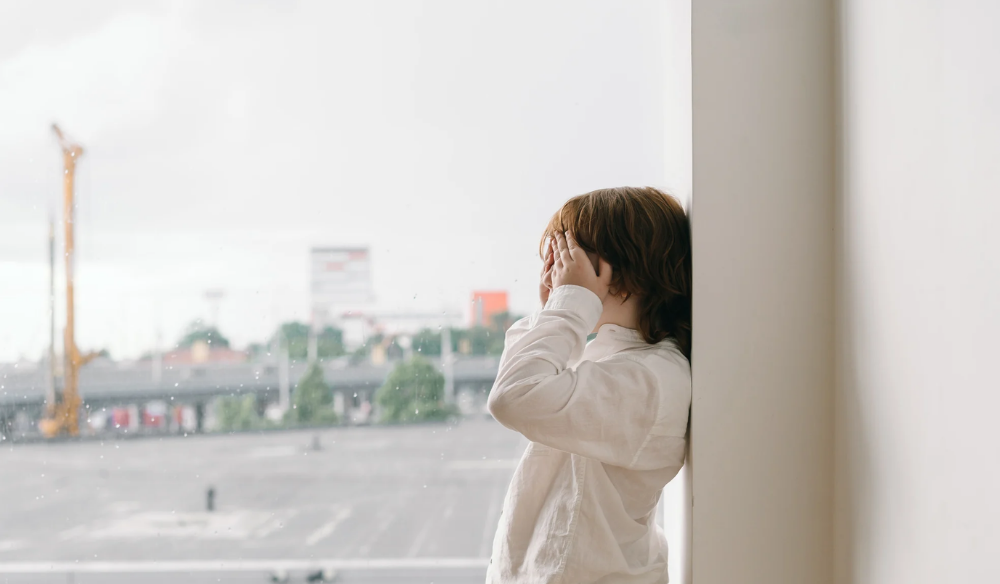Child looking out of a window towards the harbour