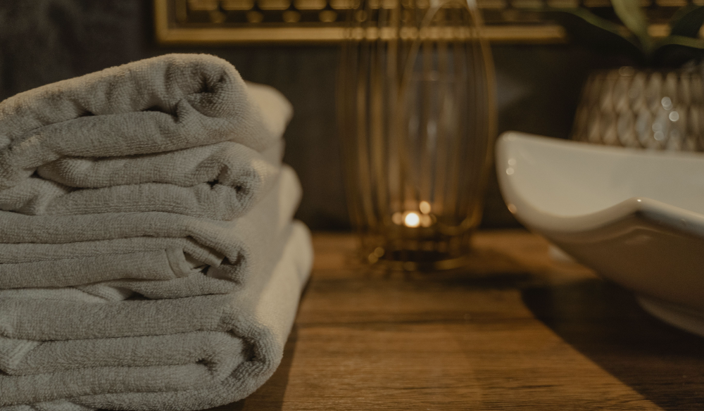 Folded spa towels beside a candle