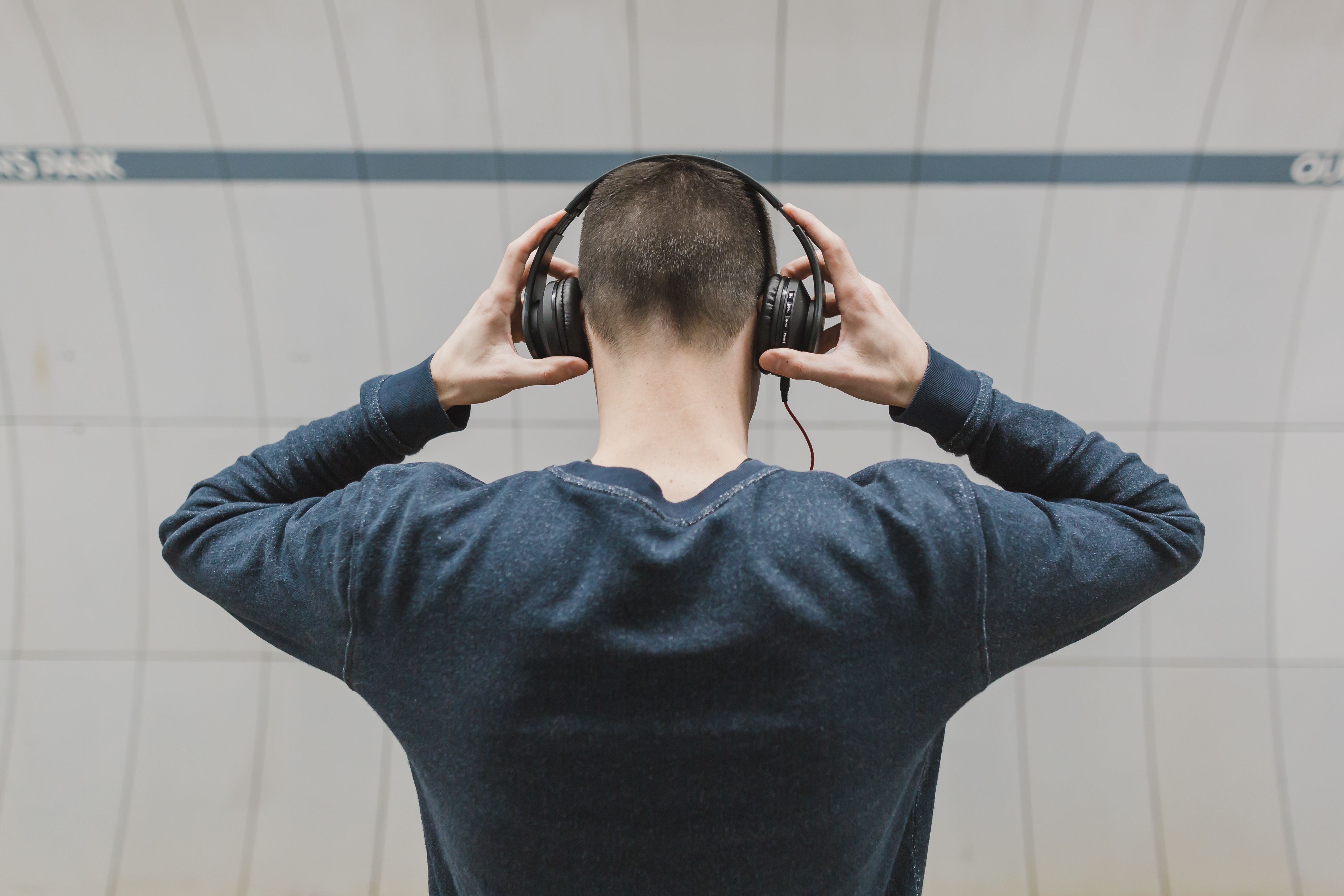 Man adjusting over-ear headphones, seen from behind