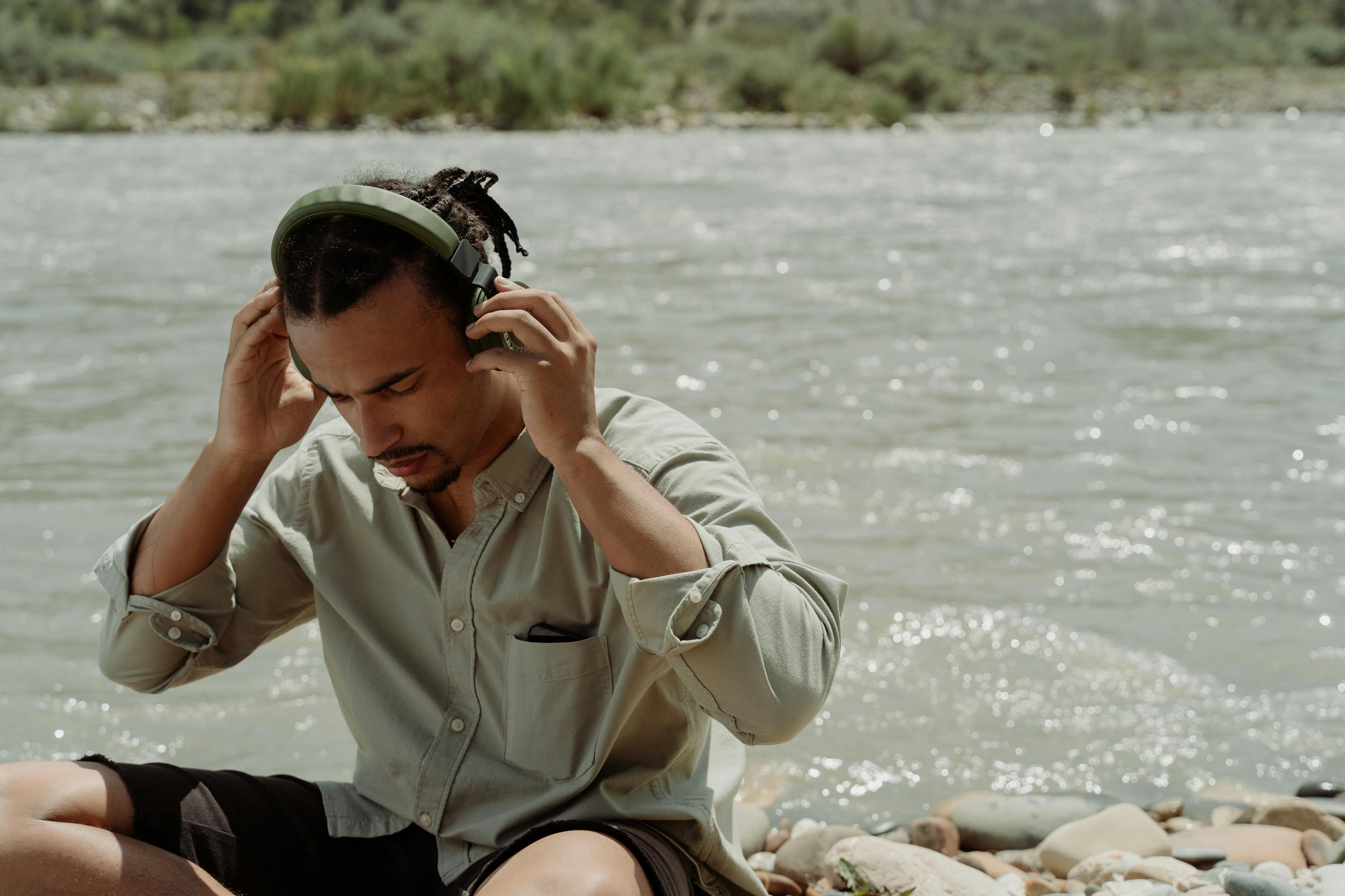 Man listening to music with headphones beside a mountain river