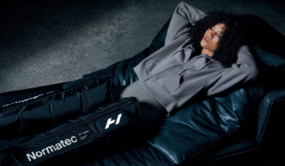 Person relaxing in Normatec recovery boots in low light